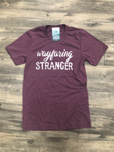 Blush tee with vintage distressed print that says Wayfaring Stranger. Displayed on hardwood floor.